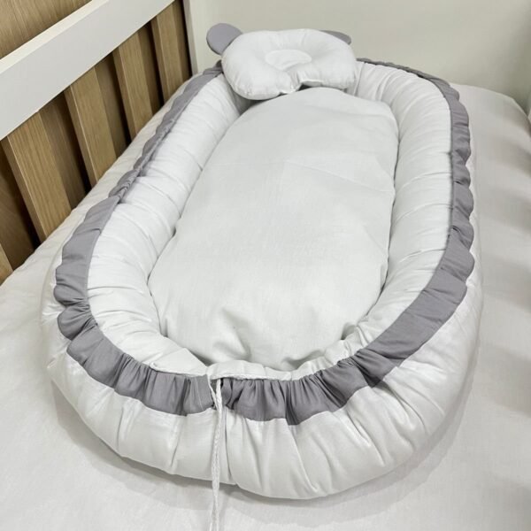 Ninho redutor de berço branco e cinza.